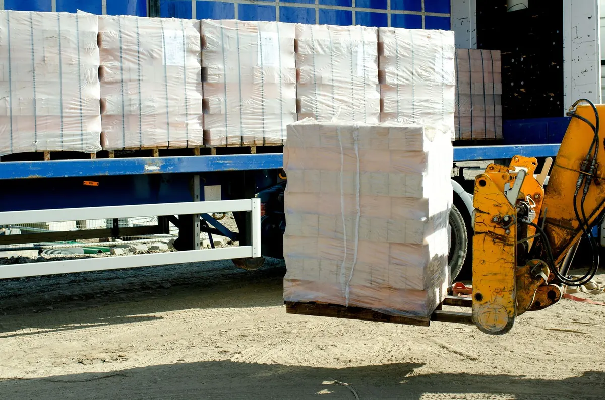 Forklift unloading a wrapped pallet from a lorry